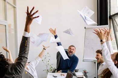 A diverse office team celebrating with papers in the air, showing teamwork and success.